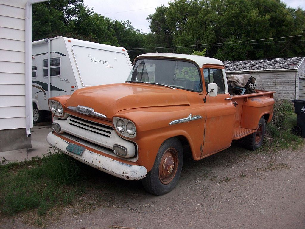 Photo of an old 1930's Chevy classic truck sitting in a driveway next to a camper trailer