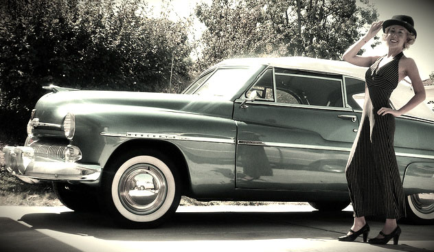 Photo of restored classic sedan with women posing next to it